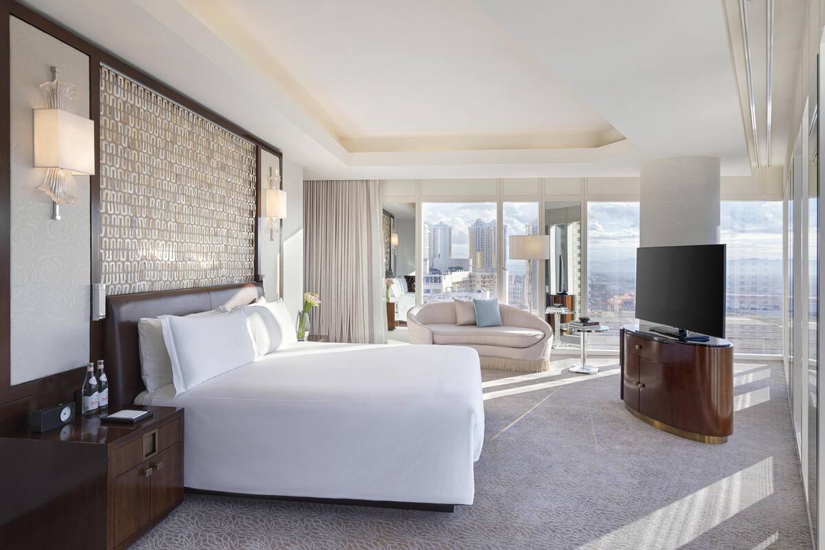 Une chambre d’hôtel moderne avec un grand lit, un canapé, une télévision et une vue sur la ville.