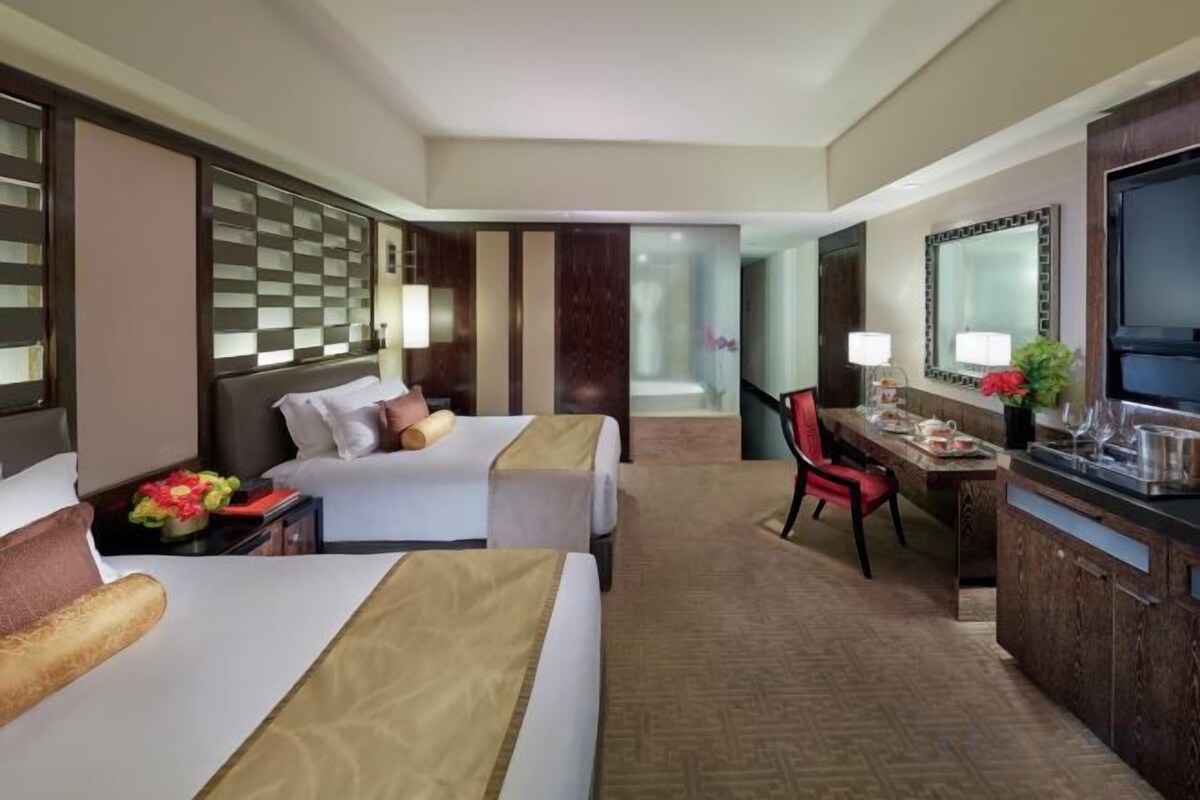 Une chambre d’hôtel avec deux lits, un bureau, une chaise et un téléviseur.
