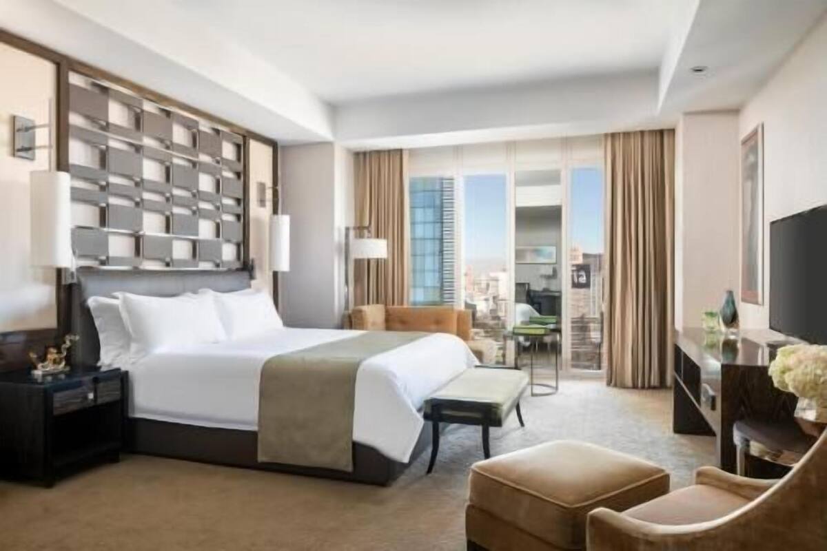 Une chambre d’hôtel avec un grand lit, un bureau, une chaise, une télévision et une vue sur la ville.
