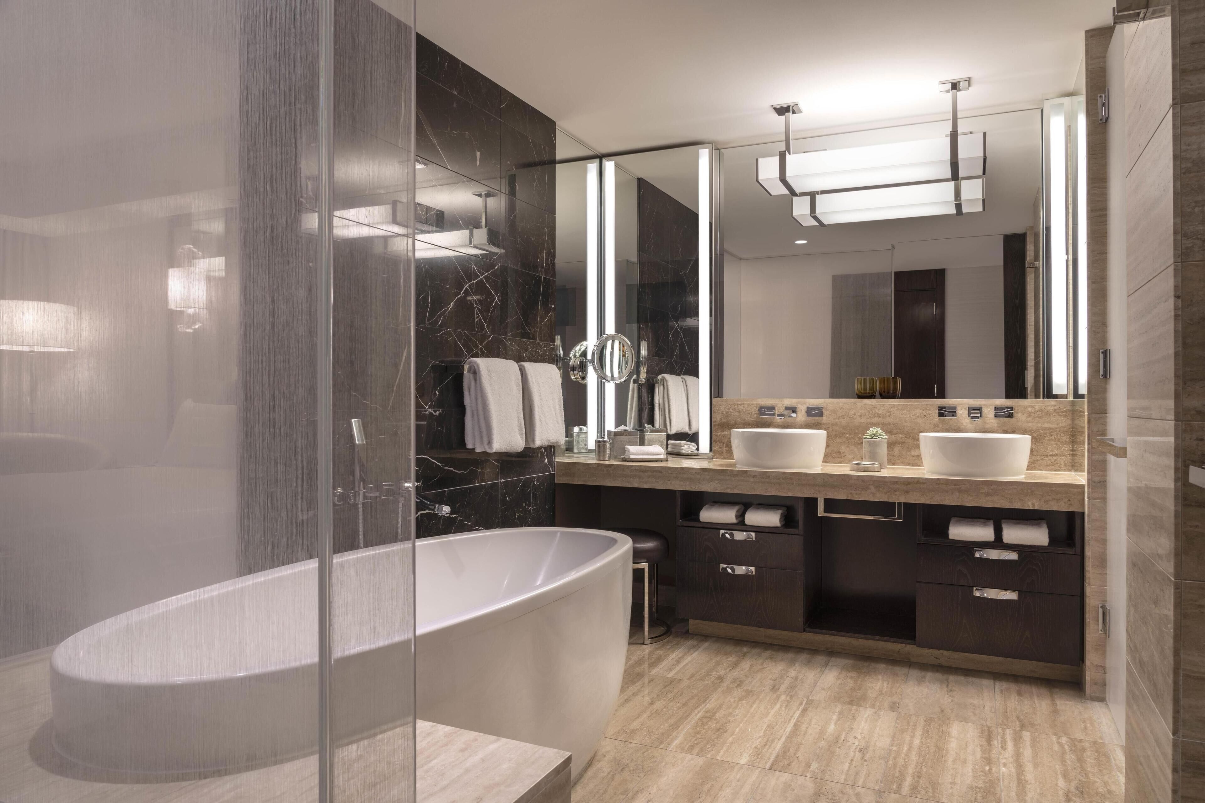 A modern bathroom with a freestanding bathtub, a vanity with two sinks, and a large mirror.