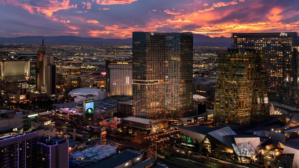 A cityscape at dusk with prominent high-rise buildings, including a hotel with a distinctive facade and a casino.