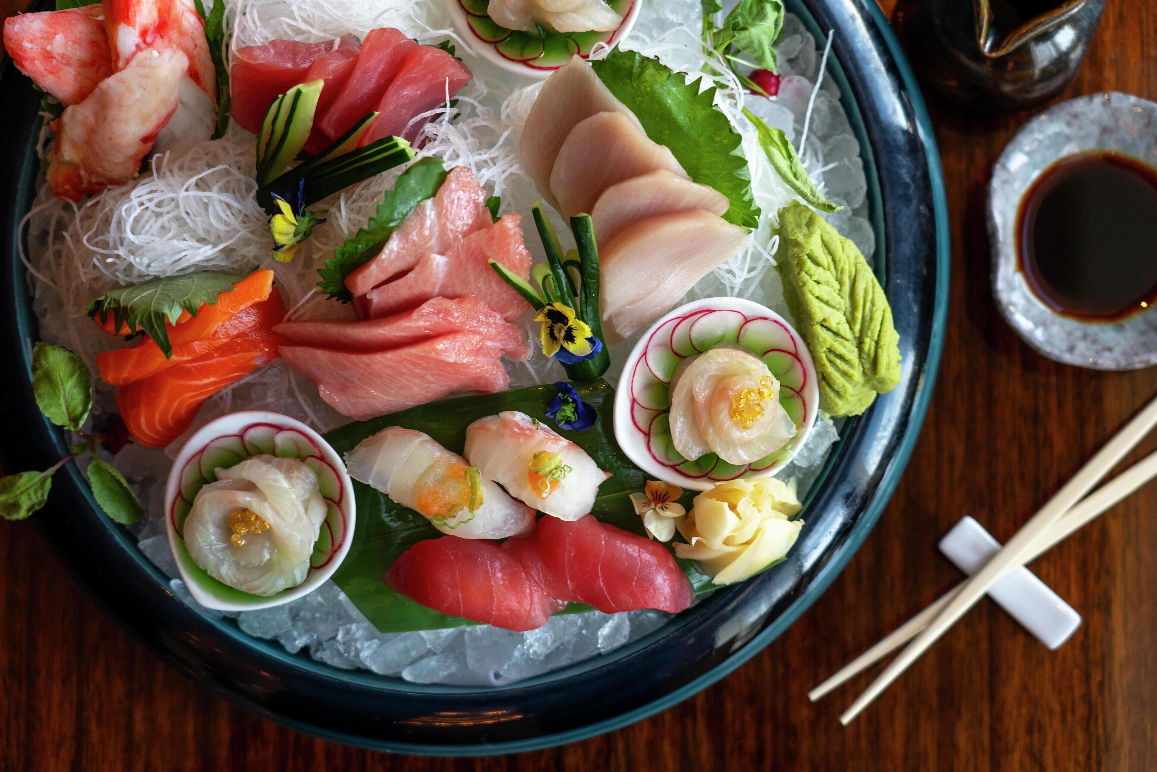 Een sushi schotel met diverse soorten vis en garneringen op ijs.