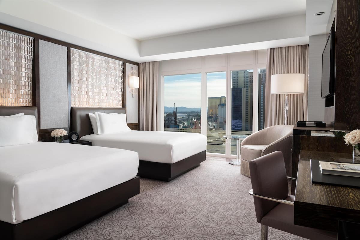 Une chambre d’hôtel avec deux lits, un bureau et une vue sur la ville.