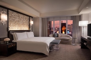 Une chambre d’hôtel avec un grand lit, un canapé, une télévision et une vue sur la ville.