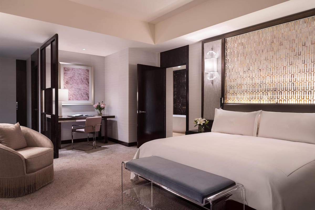 Une chambre d’hôtel moderne avec un grand lit, un bureau avec une chaise, un canapé et un banc.