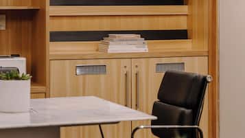 Un salón de conferencias con un armario de madera, un documento enmarcado y una silla de oficina negra.