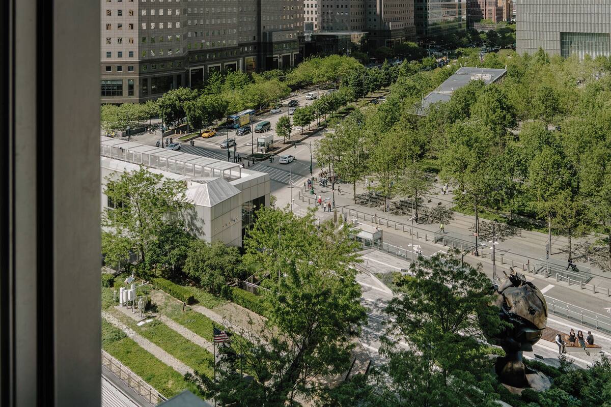 A cityscape with modern skyscrapers, a central plaza with trees, and a large sculpture.