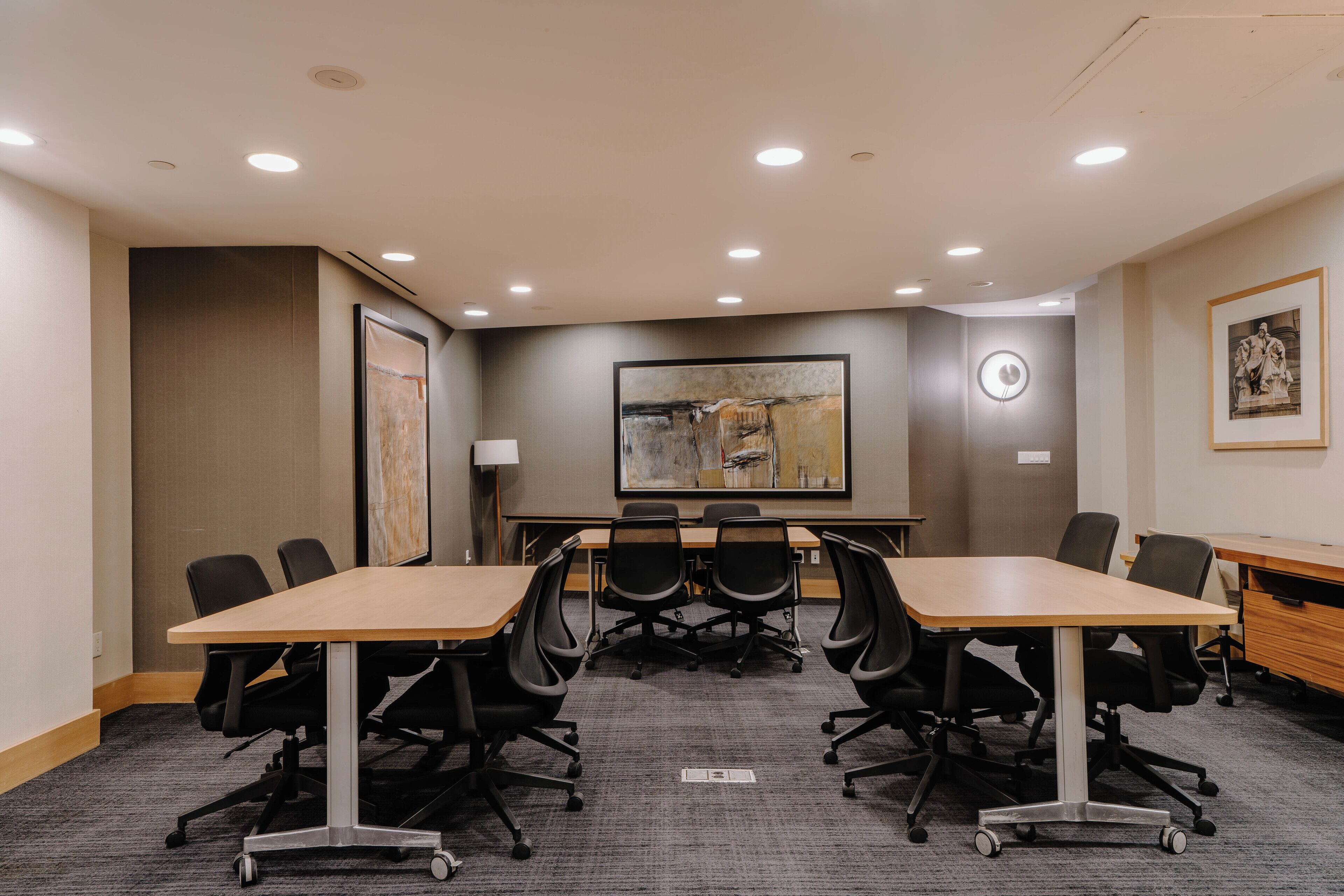 Un salón de conferencias con una gran mesa, sillas de oficina negras e iluminación empotrada en el techo.
