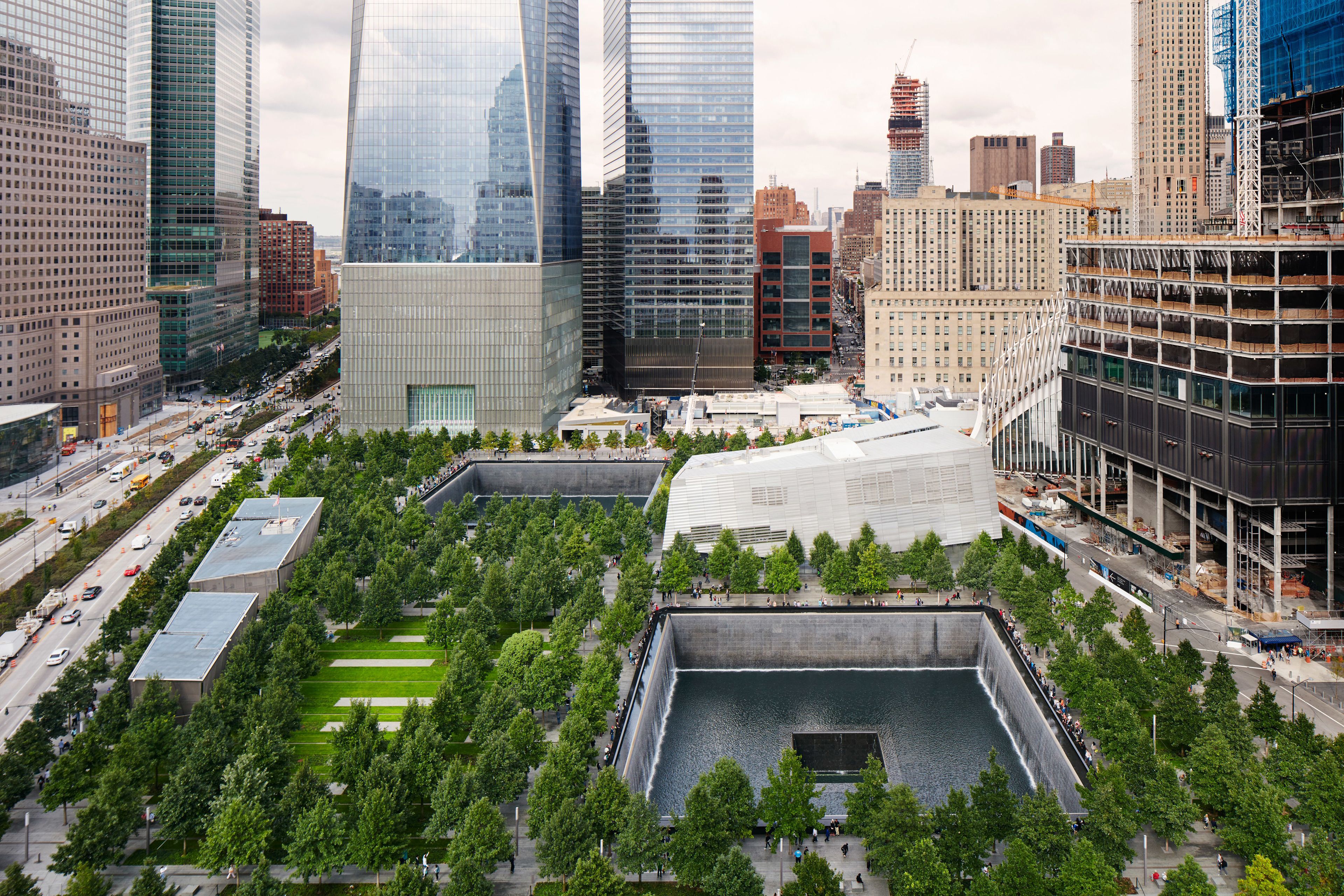 A high-rise urban area with modern buildings, a large open plaza with trees, and a water feature.