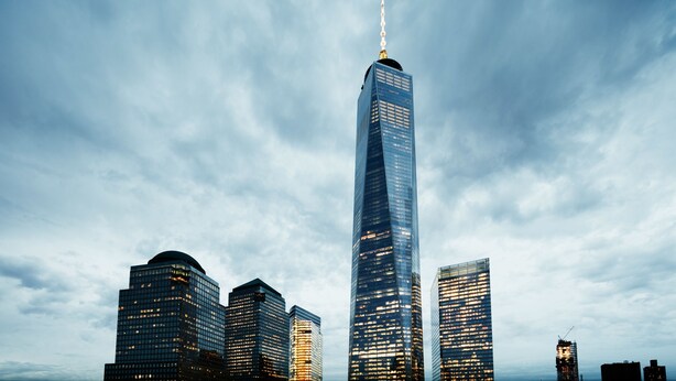 A cityscape with a prominent skyscraper featuring a spire, surrounded by other high-rise buildings. - World Center Hotel (New York)
