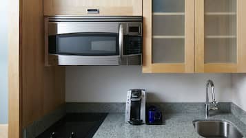 Una cucina con forno a microonde integrato, macchina del caffè e lavello in acciaio inossidabile.