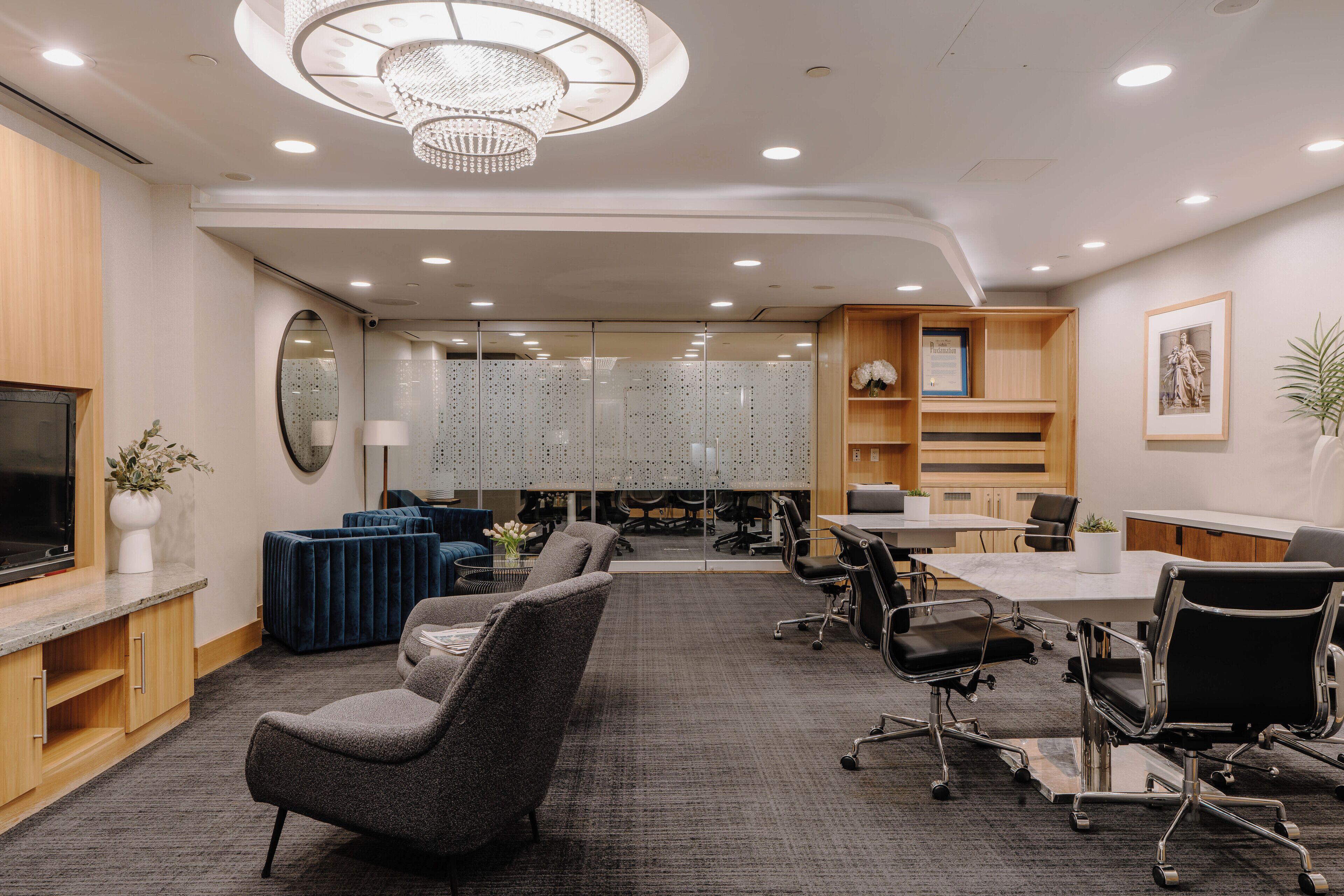 A modern conference room with a large table, several chairs, a television, and a chandelier.