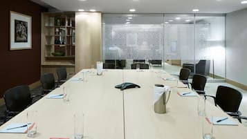 A conference room with a long table, chairs, and glass partitions.