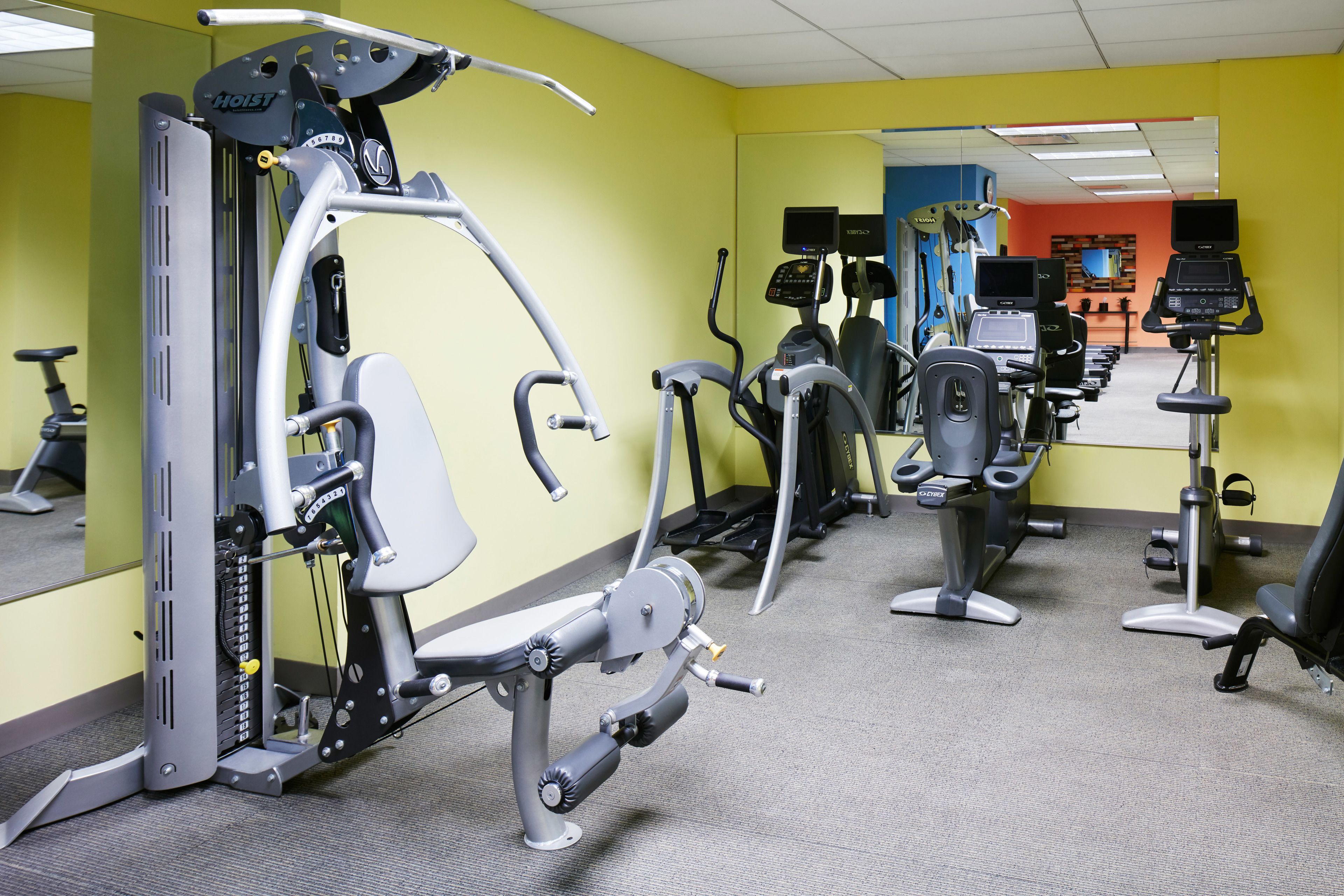 A gym with various exercise machines, including cardio and strength equipment, arranged in a spacious layout.