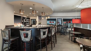 A modern bar area with a curved counter, multiple seating options including bar stools and tables, and pendant lighting. - Best Western Premier Crown Chase Inn & Suites (Denton)