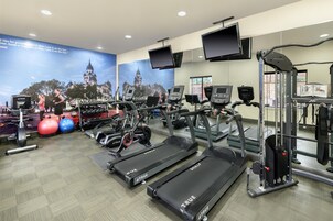 Un gimnasio con cintas de correr, pelotas de ejercicios y máquinas de pesas.