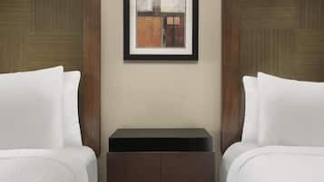 A hotel room with two beds, a small bedside table, and a framed artwork on the wall.