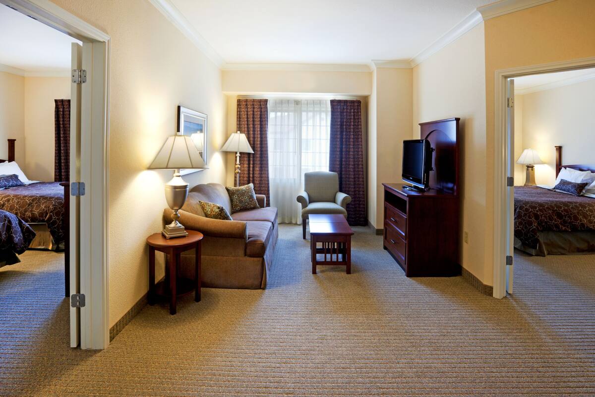 Una camera d'albergo con divano, poltrona, televisione e un tavolino.
