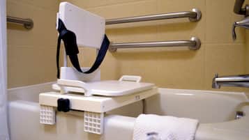 Une salle de bain avec une baignoire, des barres d’appui et une serviette blanche.