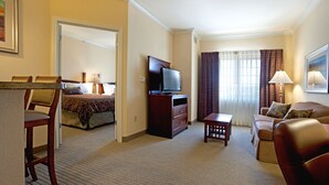 A hotel room with a bed, a TV, a sofa, a desk, and a chair.