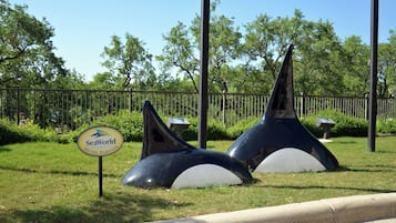 A grassy area with a sign for SeaWorld Hotel Partner and two large, dark, conical structures.