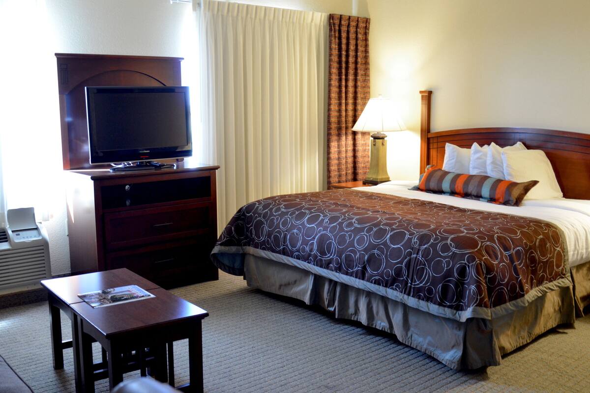 Una camera d'albergo con un letto, una TV su un mobile, una scrivania e una lampada.