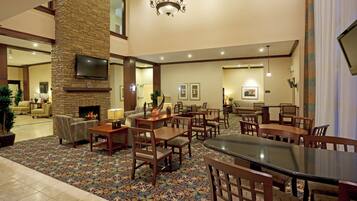 A spacious hotel lobby with a fireplace, dining area, and seating arrangements.