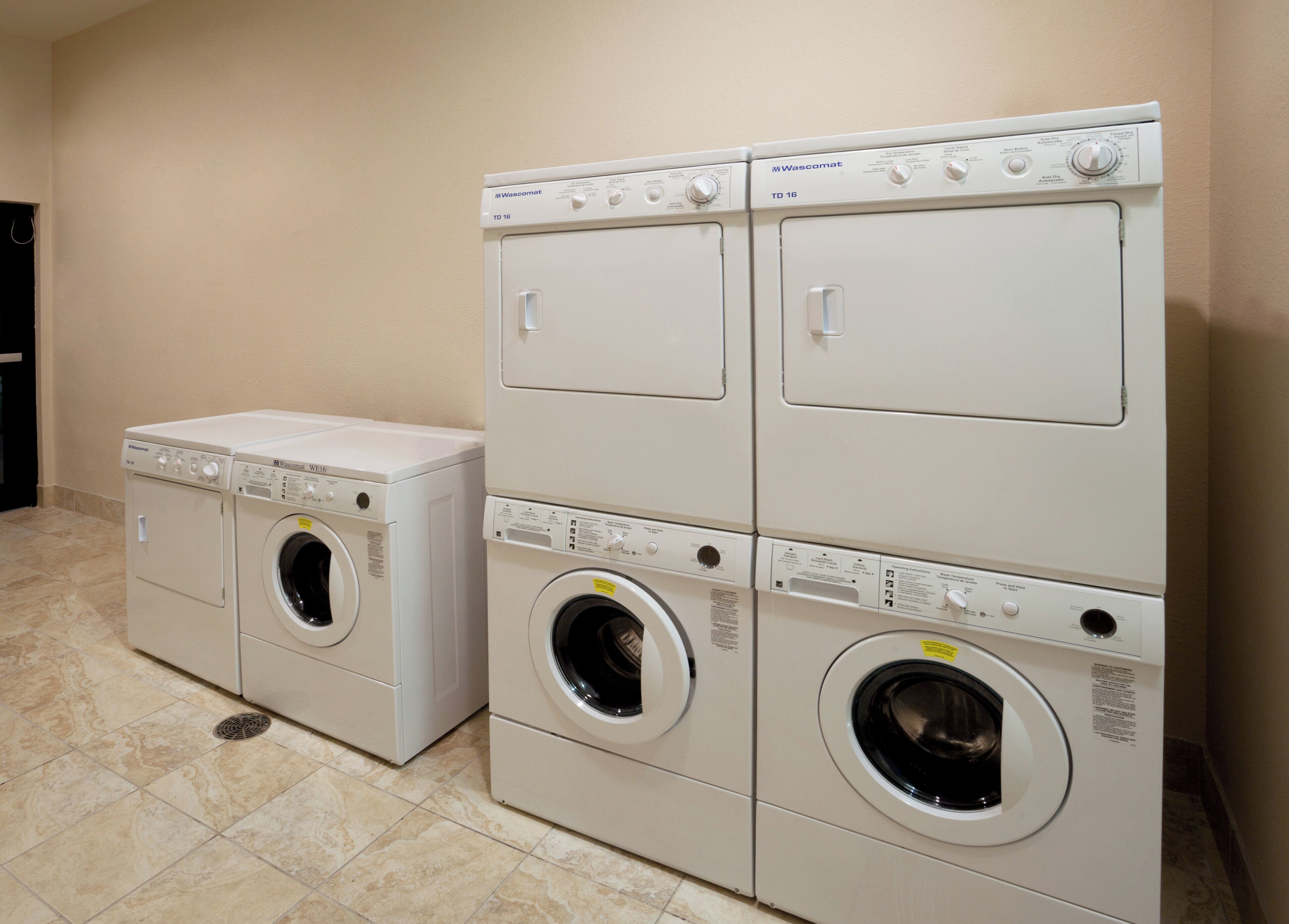 A laundry area with two stacked washing machines and a dryer.
