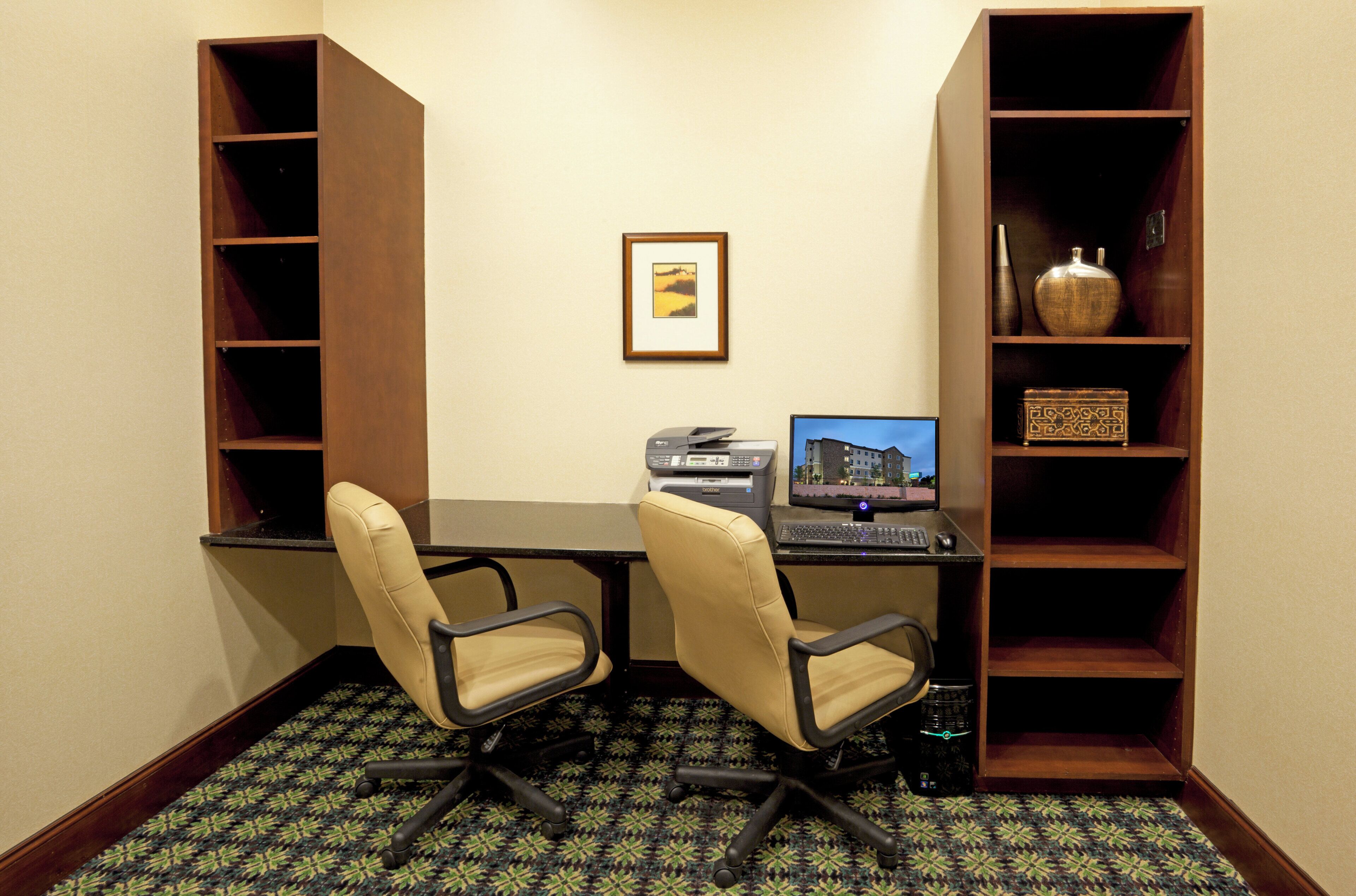 A small office space with two chairs, a desk, a computer, and a bookshelf.