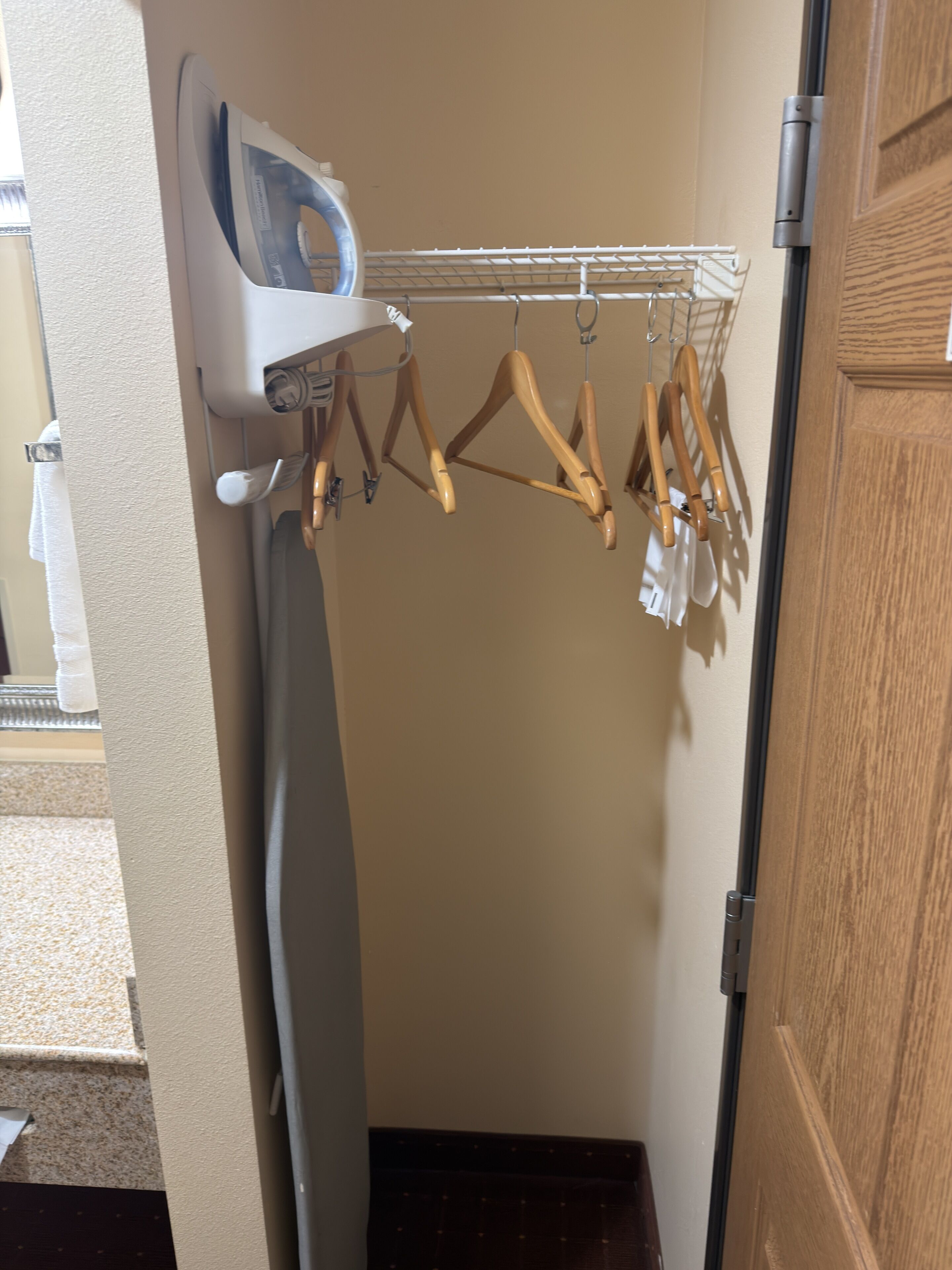 A laundry area with an iron, wooden hangers, and a drying rack.