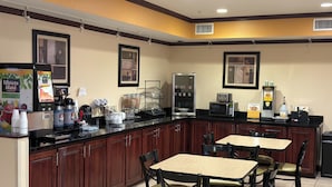 A hotel kitchen with a buffet setup, including a refrigerator, microwave, and coffee station.