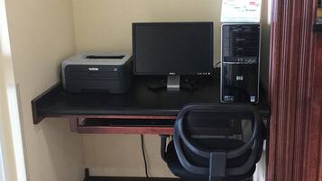 A small office space with a desk, a desktop computer, a printer, and an office chair.