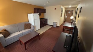 A compact living space with a kitchenette, a sofa, a dining table, and a TV.