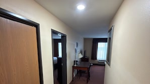 A hallway with a wooden door, a dining table with chairs, and a ceiling light.