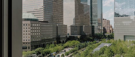 A cityscape with modern skyscrapers, a central plaza with a sculpture, and a clear sky.