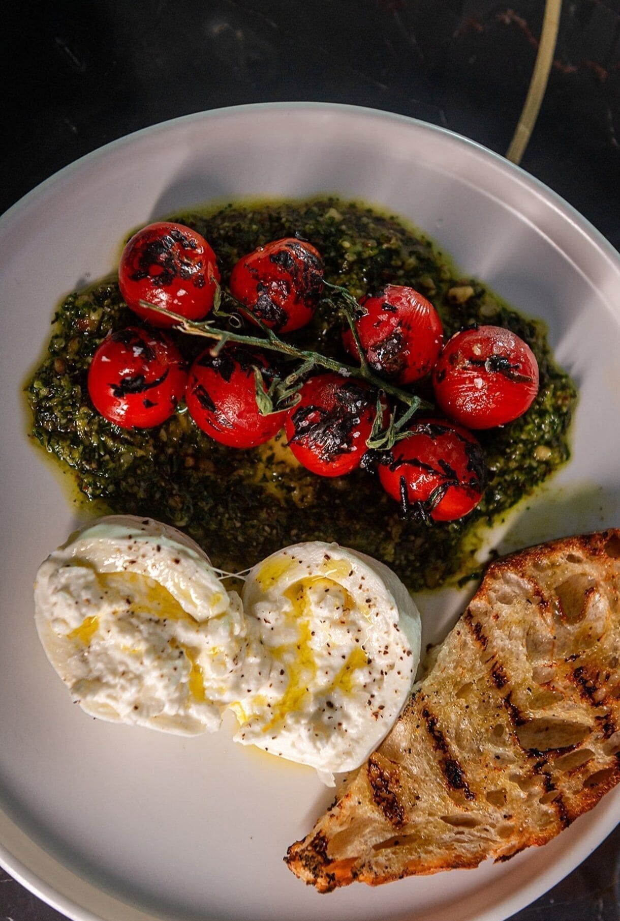 A plate with grilled tomatoes, a poached egg, and grilled bread.