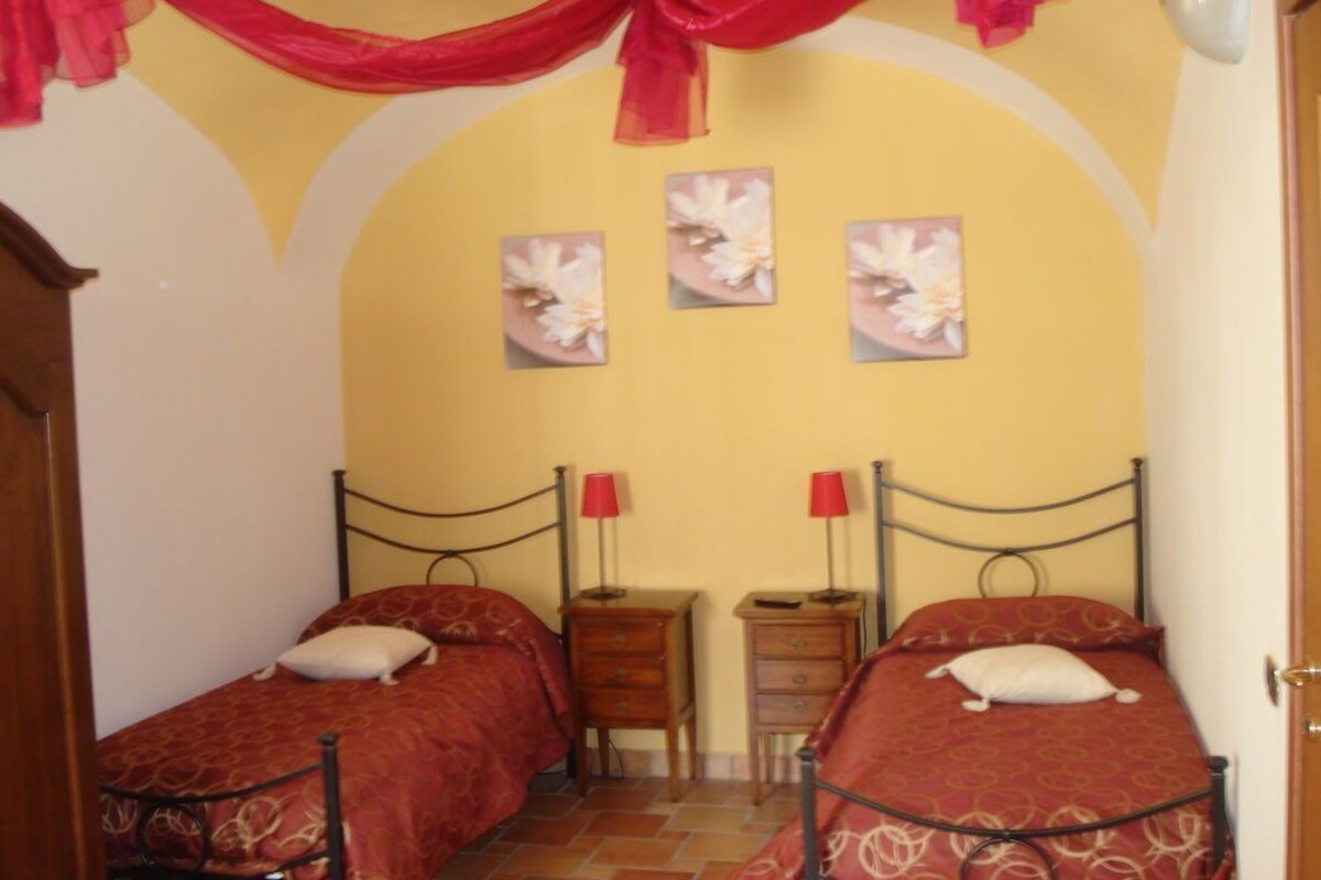 Une chambre avec deux lits, une commode en bois et trois lampes fixées au mur.