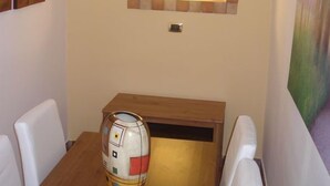 Un coin repas avec une table en bois, des chaises blanches, un miroir avec un cadre en briques et un luminaire suspendu.