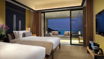 A hotel room with two beds, a television, and a view of the sea.