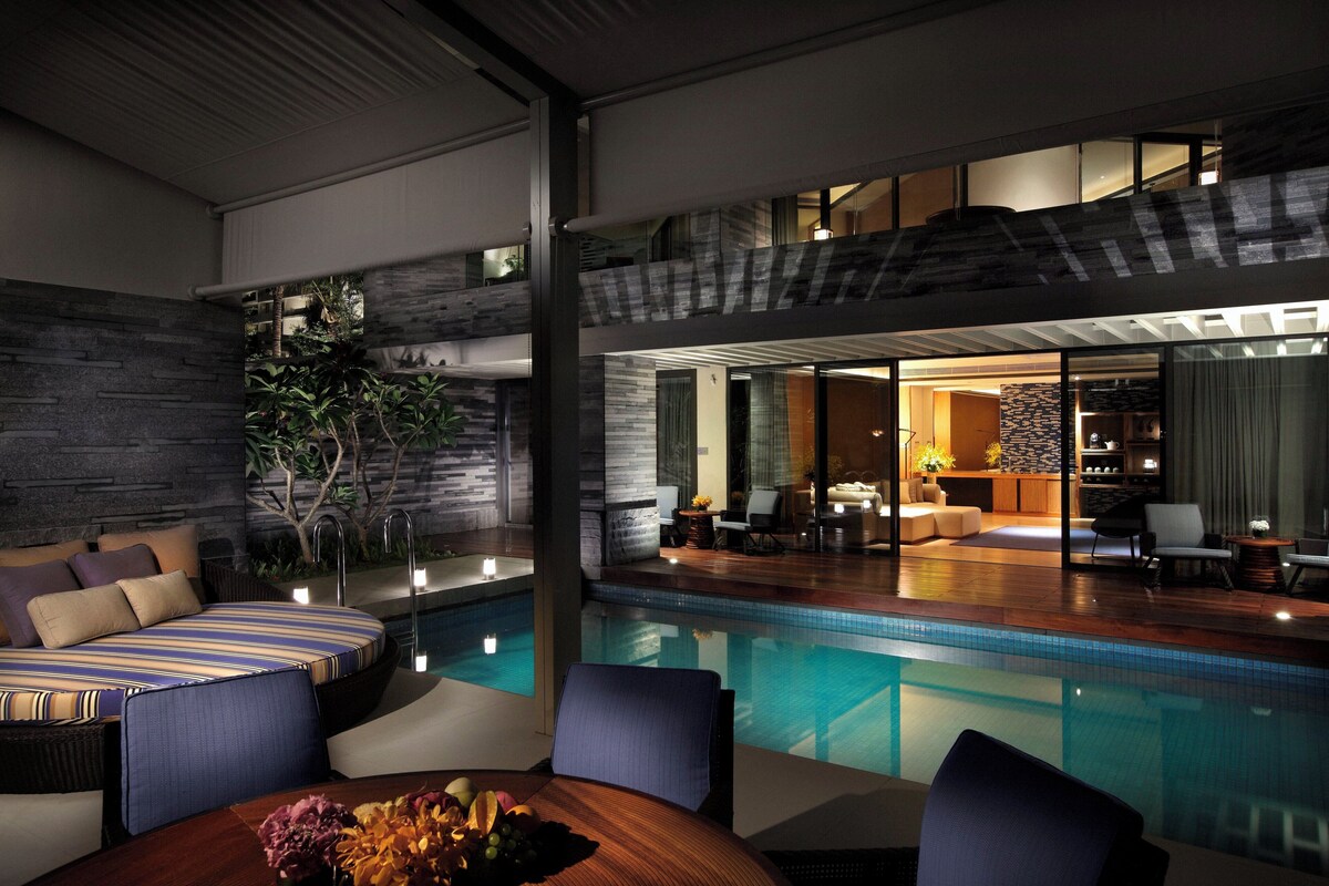 Un área de piscina interior moderna con una zona de estar y una mesa de comedor.