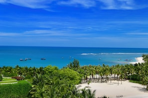 A beach with palm trees, boats, and a clear blue sky. - InterContinental Sanya Resort by IHG (Sanya)