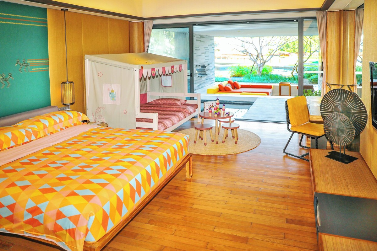Habitación de hotel con una cama grande, una mesita con sillas, un ventilador y vistas al exterior.