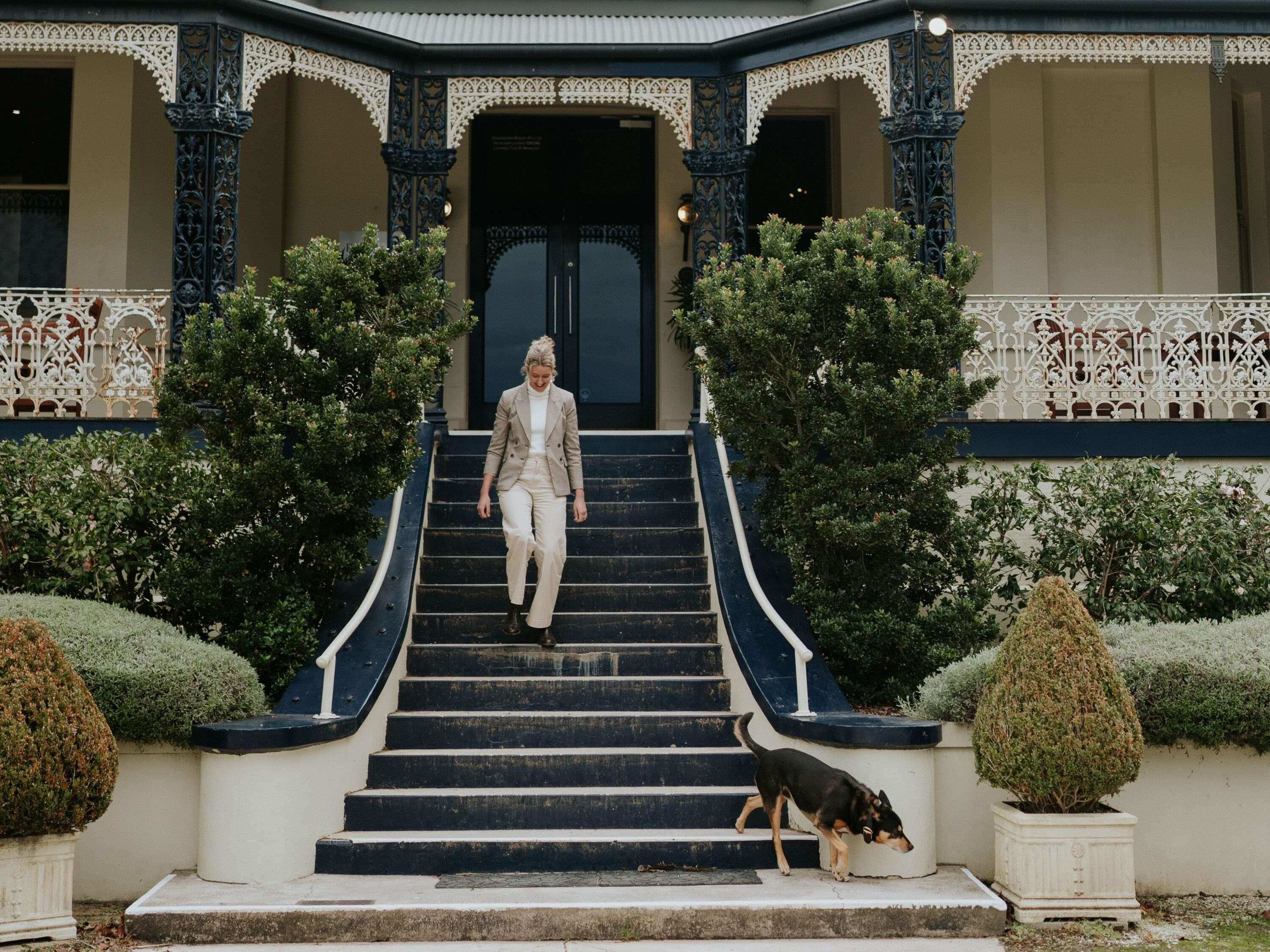 A person descending a staircase with ornate railings, surrounded by well-maintained shrubbery.