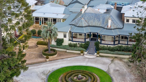 A large estate with a central circular garden, a grand staircase leading to a covered porch, and multiple buildings with varied roof designs. - Peppers Craigieburn (Bowral)