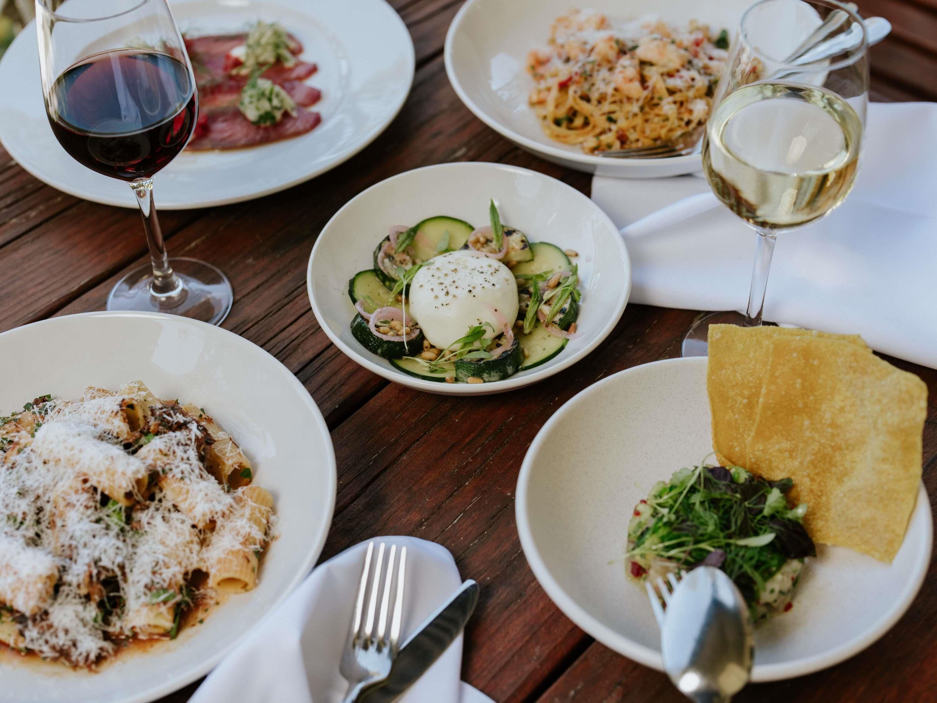 Une table dressée avec différents plats, notamment des pâtes, une salade et une assiette avec une tranche de pain.
