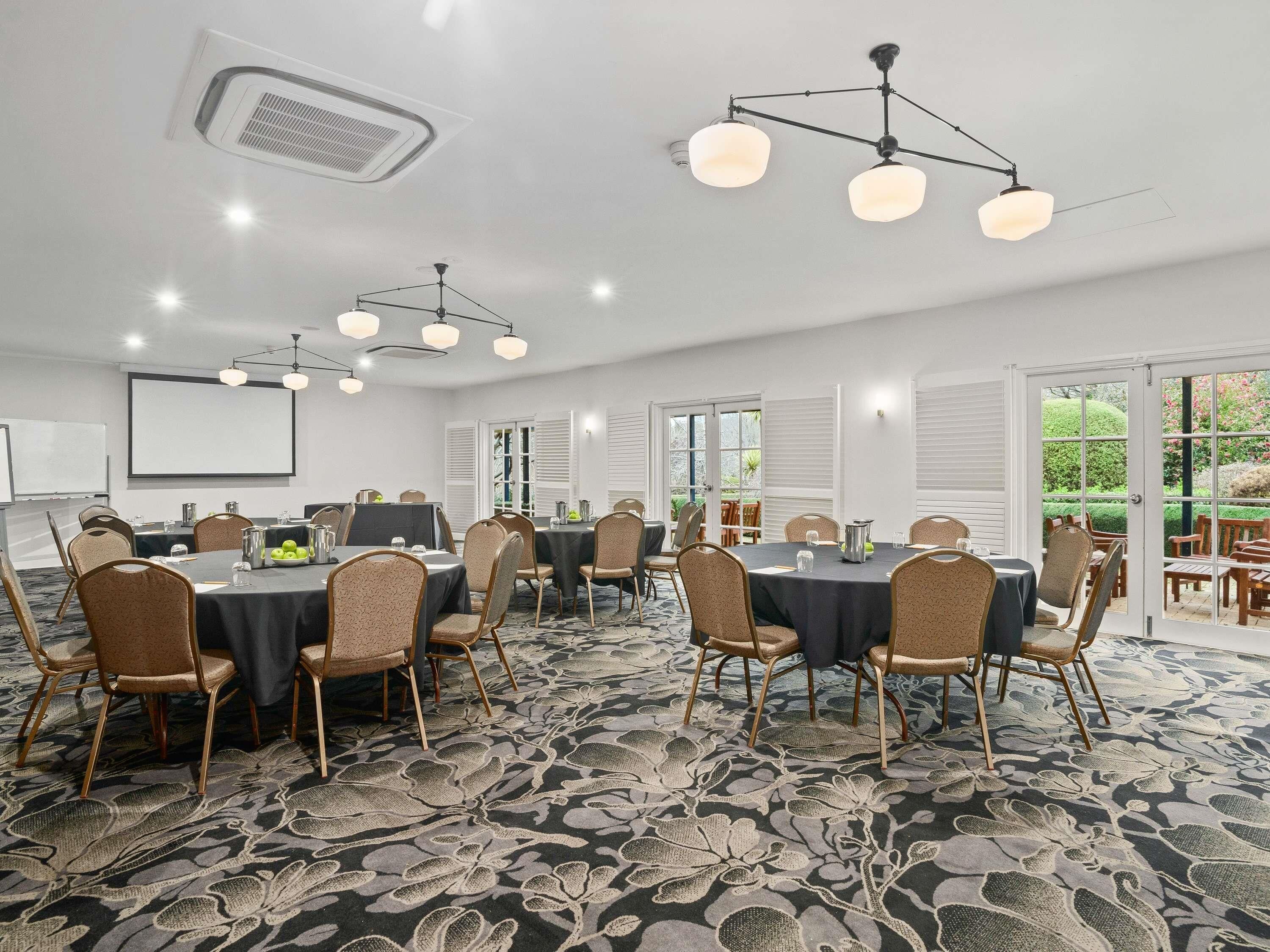 A conference room with multiple tables, chairs, and ceiling lights.