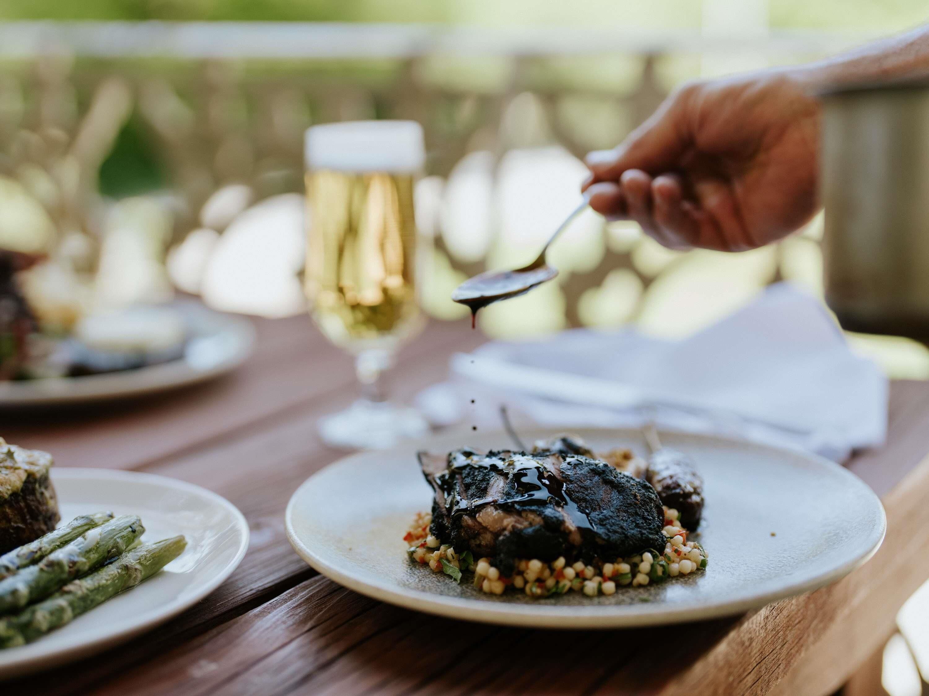 A dining table with plates of food, a glass of wine, and a napkin.