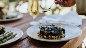 Une table à manger avec des assiettes remplies de nourriture, un verre de vin et une serviette.