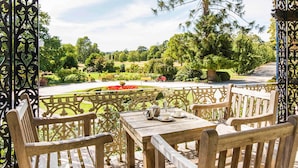 An outdoor seating area with a table and chairs, a view of a garden, and a decorative metal fence. - Peppers Craigieburn (Bowral)