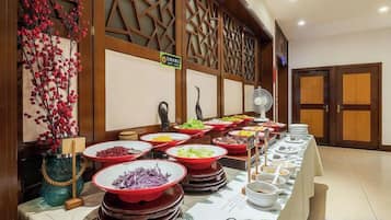Una mesa de buffet con diversos alimentos y un florero decorativo.